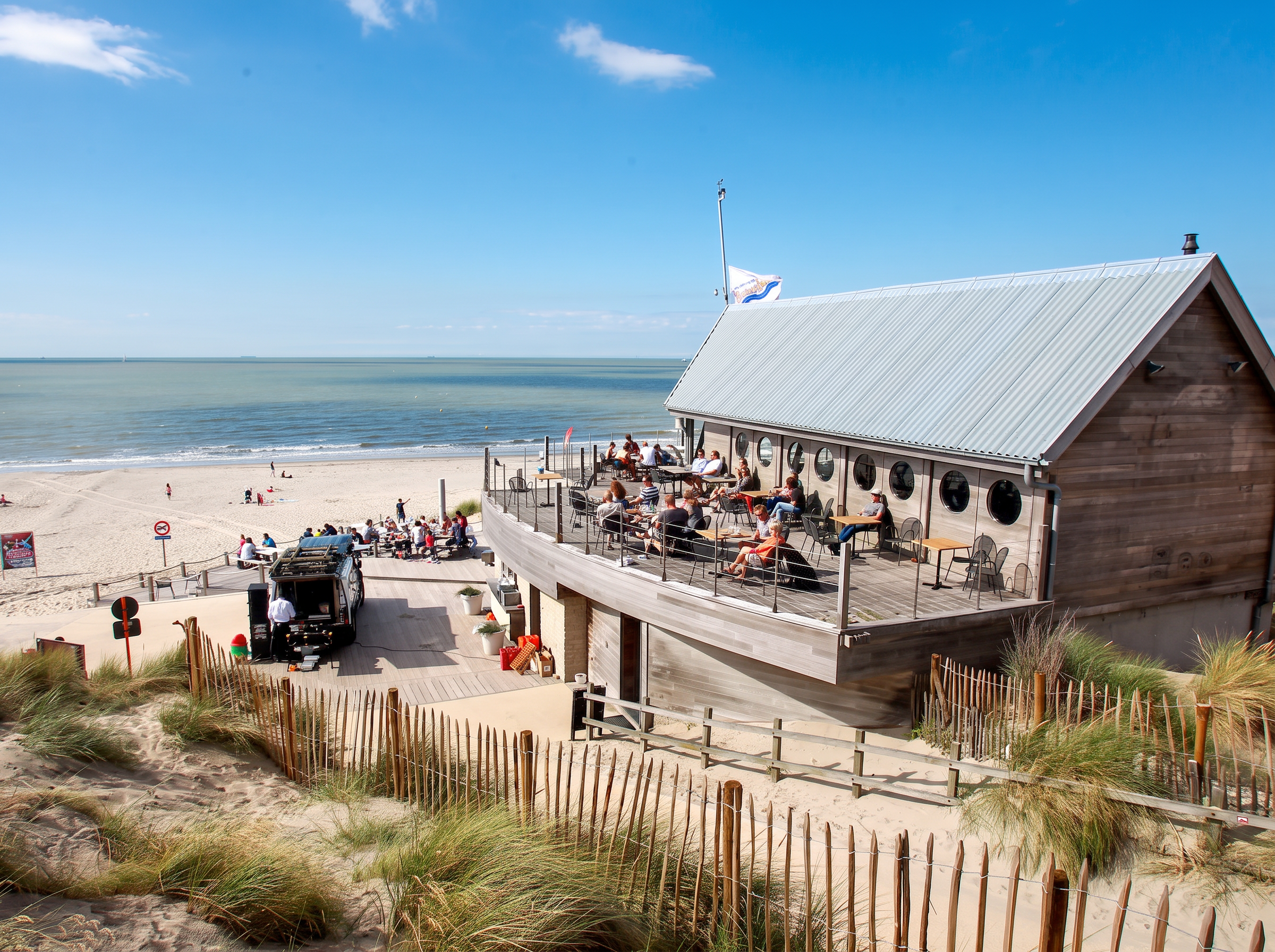 Een zonnig strandterras in Bredene, met uitzicht op zee en duinen op de voorgrond